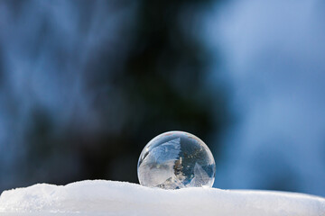One frozen soap bubble on white snow with dark background