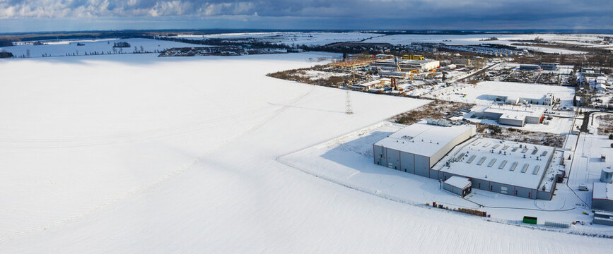Aerial panoramic winter view of a factory next to a snowy field