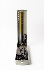An old mercury sphygmomanometer on a solid color background