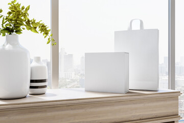Sunny city view from room with light vases on light wooden surface and blank white paper bag and box. Mockup