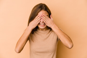 Young skinny caucasian teenager girl covers eyes with hands, smiles broadly waiting for a surprise.