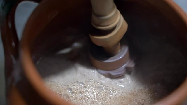 Shaking hot cocoa in a clay pot with Mexican molinillo