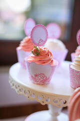 Delicious wedding reception candy bar, dessert table. Pink Sweet table with roses flowers, cupcakes for birthday party. Festive decor in restaurant. Anniversary dating celebration. Delicious buffet