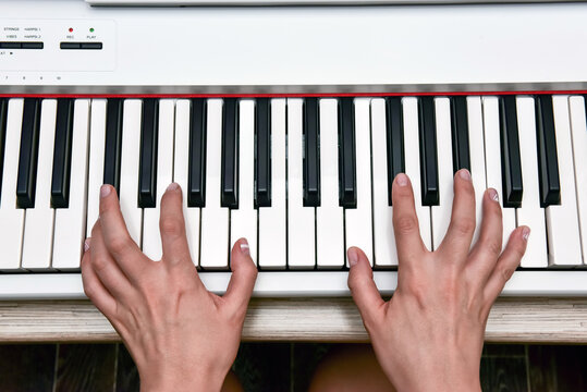 Woman's hands playing electronic digital piano at home. The woman is professional pianist arranging music using piano electronic keyboards. Musician practicing keyboard composing music