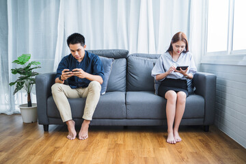Obraz premium Asian businessman woman couple lifestyle minimal relaxing using playing mobile phone tablet devices technology surfing online internet casual comfortable relaxing taking break time living room lounge