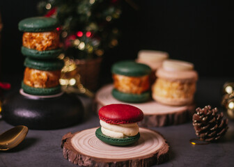 red macaroon,white macaroon,green macaroon on the wood plate with christmas tree on dark background