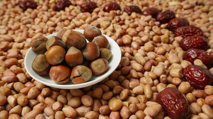 A plate of chestnuts on a background of dried peanuts and red dates, healthy food, focus on foreground