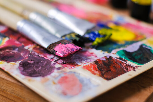 Close up colour pallet and paint brush paint with mixed colourful paint mixture, vivid vibrant artistic creativity design.