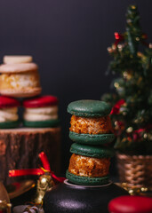 red macaroon,white macaroon,green macaroon on the wood plate with christmas tree on dark background