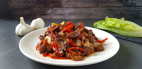 A plate of stir-fried spicy and hot beef, lettuce and garlic on the table, homemade food
