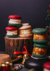 red macaroon,white macaroon,green macaroon on the wood plate with christmas tree on dark background