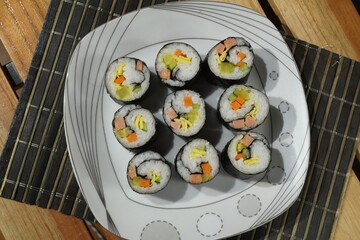 Top view of nine sushi rolls arranged on white plate, homemade traditional Asian cuisine