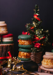 red macaroon,white macaroon,green macaroon on the wood plate with christmas tree on dark background