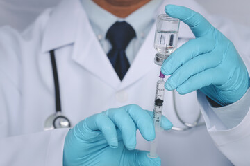 Male doctor hands on blue gloves with stethoscope on shoulder holding syringe and Covid-19 coronavirus vaccine vial or drug on white background. Healthcare And Medical concept