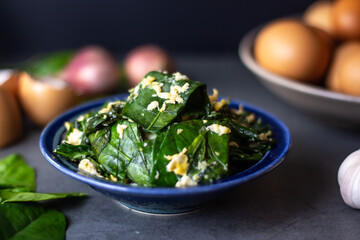 Stir-fried Malindjo leaves with Egg on dark background. (Thai name is Bai Lieng Pad Kai),the leaves is local plant of Southern Thailand, believe it is healthy food