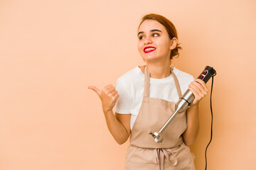 Young skinny arab cook woman points with thumb finger away, laughing and carefree.