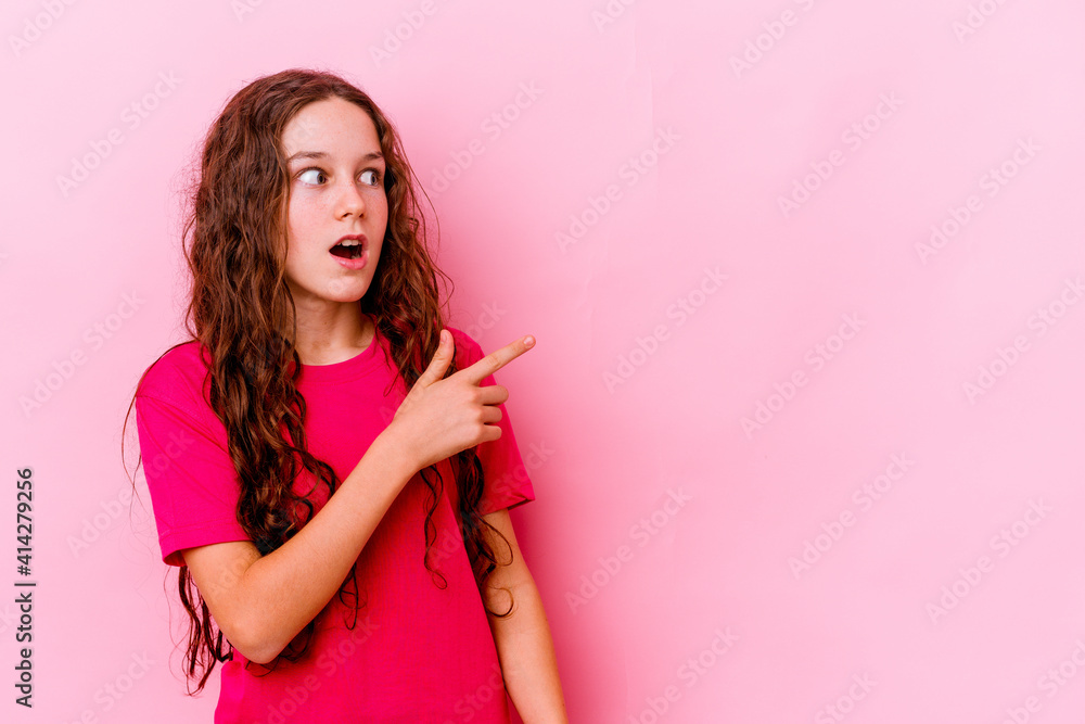 Wall mural Little caucasian girl isolated on pink background pointing to the side