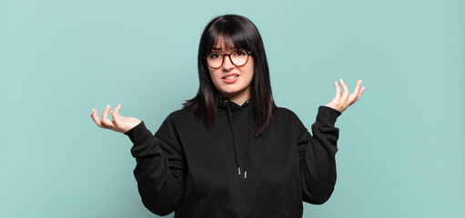 plus size pretty woman shrugging with a dumb, crazy, confused, puzzled expression, feeling annoyed...