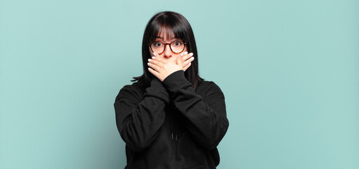 plus size pretty woman covering mouth with hands with a shocked, surprised expression, keeping a...