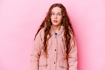 Little caucasian girl isolated on pink background being shocked because of something she has seen.