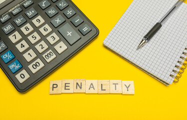 Word penalty made with wood letters on yellow background and modern calculator with pen and notebook. Copy space. Economy, money planning. Business, finance concept. Tax burden. Taxes and taxation.