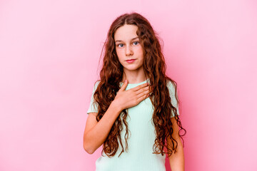 Little caucasian girl isolated on pink background taking an oath, putting hand on chest.