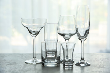 Different elegant empty glasses on grey table indoors