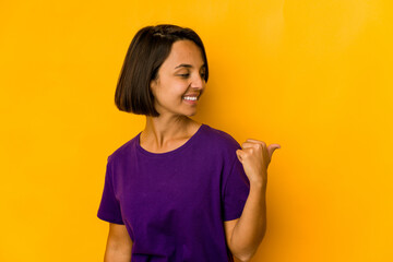 Young hispanic woman isolated on yellow points with thumb finger away, laughing and carefree.
