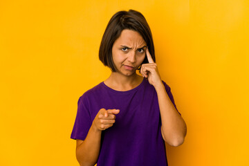 Young hispanic woman isolated on yellow pointing temple with finger, thinking, focused on a task.