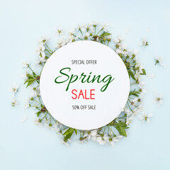 Text Spring Sale. Special offer. 50% off. Round frame with spring flowers. Flowers on cherry tree branches in form of wreath on blue background. Leaf pattern. Flat lay, top view, copy space. Mockup