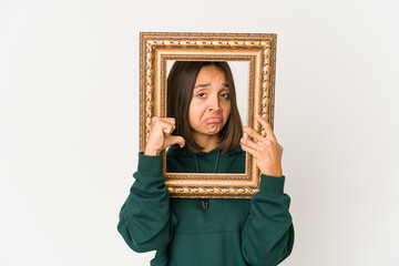 Young hispanic woman holding an old frame feels proud and self confident, example to follow.