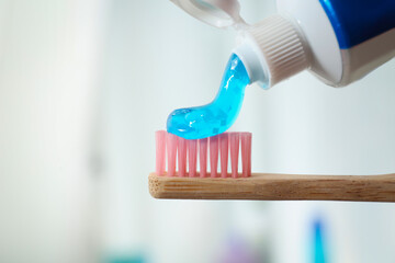 Applying toothpaste on brush against blurred background, closeup