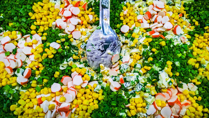 fresh green salad from onions, corn, cucumbers, crab sticks and mayonnaise closeup with a spoon © wimages