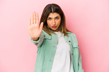 Young indian woman isolated on pink background standing with outstretched hand showing stop sign,...