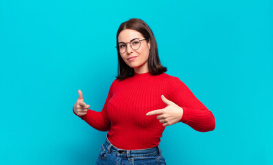 young pretty casual woman looking proud, arrogant, happy, surprised and satisfied, pointing to...