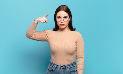 young pretty casual woman pointing at camera with an angry aggressive expression looking like a...