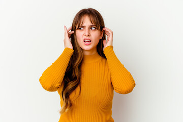 Young caucasian cute woman isolated on white background covering ears with fingers, stressed and desperate by a loudly ambient.