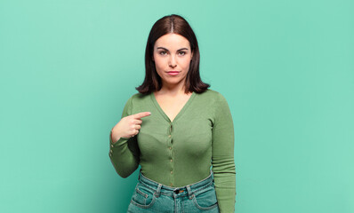 young pretty casual woman looking proud, confident and happy, smiling and pointing to self or...