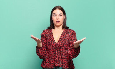 young pretty casual woman feeling extremely shocked and surprised, anxious and panicking, with a...