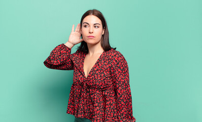 young pretty casual woman looking serious and curious, listening, trying to hear a secret...