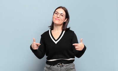 young pretty casual woman looking proud, arrogant, happy, surprised and satisfied, pointing to...