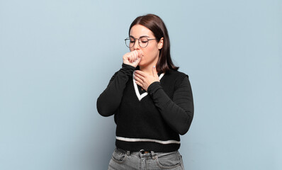 young pretty casual woman feeling ill with a sore throat and flu symptoms, coughing with mouth...