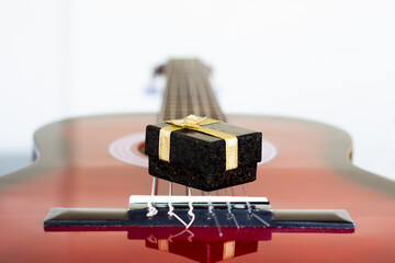 Box and Guitar. cardboard jewelry box with gold color ribbons above guitar strings