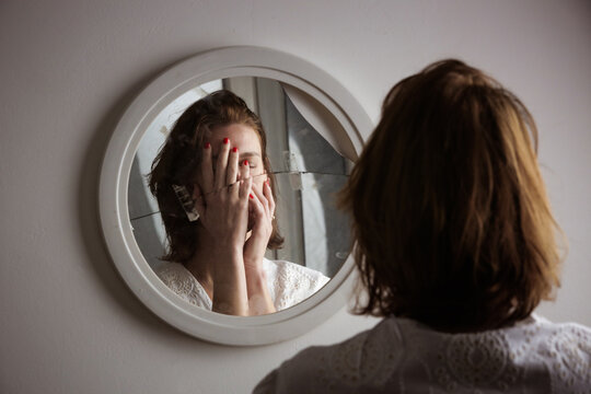 Reflection of a woman's face in broken mirror. Depression, anxiety, phobia, suicide and mental health concept.
