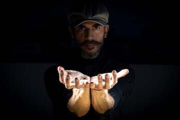 Male model with cap and open hands black background