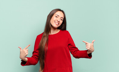 young pretty casual woman looking proud, arrogant, happy, surprised and satisfied, pointing to...