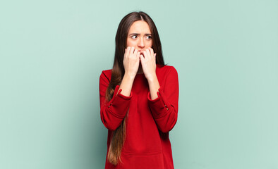young pretty casual woman looking worried, anxious, stressed and afraid, biting fingernails and...