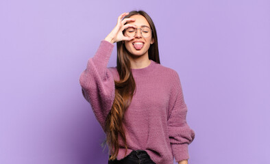 young pretty casual woman smiling happily with funny face, joking and looking through peephole,...