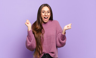 young pretty casual woman feeling happy, excited, surprised or shocked, smiling and astonished at...