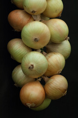 String of prized white onions black background close up